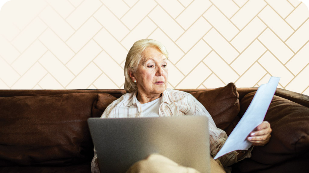 Senior woman sitting on couch with laptop comparing Roseville senior living costs